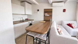 a small kitchen with a wooden table and a couch at Rena Bianca Residence 201 in Baja Sardinia +7 photos