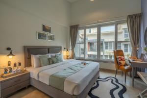 a bedroom with a bed and a desk and a window at Perfectstayz Premium Carnival Suites Near Candolim in Pilerne