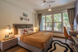 a bedroom with a bed and a desk and windows at Perfectstayz Premium Carnival Suites Near Candolim in Pilerne +164 photos