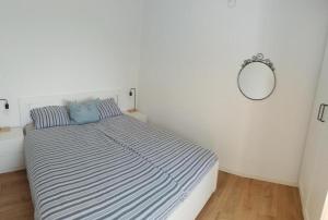 a white bedroom with a bed with a blue pillow at Olive Gardens Cottage above Portorož in Strunjan