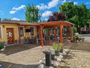 a patio with a wooden pergola and tables and chairs at Oázis Panzió in Makó