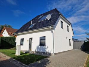 a white house with a solar roof at Villa Seeblick am Fleesensee in Göhren-Lebbin
