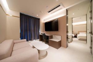 a living room with a couch and a tv at The Gleam Hotel in Incheon