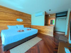 a bedroom with a bed with a wooden wall at Salty Pearl Beach Front Phuket 3 in Patong Beach