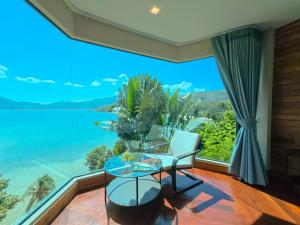 a room with a large window with a chair and a glass table at Salty Pearl Beach Front Phuket 3 in Patong Beach