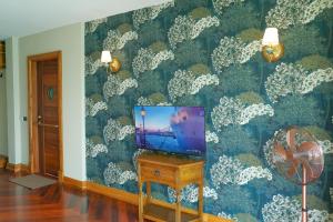 a tv sitting on a table in a room with a wallpaper at Salty Pearl Beach Front Phuket 3 in Patong Beach