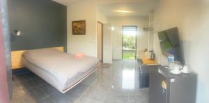 a bedroom with a large white bed and a desk at Baan Suan Papa Resort Wangmuang in Ban Nong Lom (1)