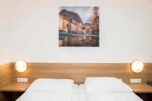 a bedroom with two beds and a painting on the wall at OEKOTEL Hohenems in Hohenems