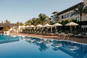 a hotel swimming pool with chairs and umbrellas at La Finca Resort in Algorfa