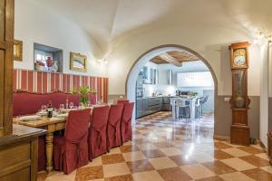 a dining room with a table with red chairs and a kitchen at ANTICA VILLA MERELLI 12, Emma Villas in Monte San Savino