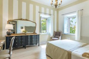 a bedroom with a bed and a mirror and a chair at ANTICA VILLA MERELLI 12, Emma Villas in Monte San Savino +55 photos