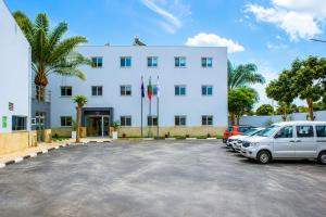 a large white building with cars parked in a parking lot at AC Hotel in Luanda