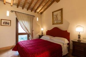 a bedroom with a large bed with a red blanket at Borgo Storico Seghetti Panichi in Castel di Lama +77 photos
