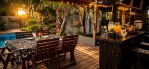 a dining table and chairs on a deck with a pool at Rose cottage Garden Suite in Pretoria