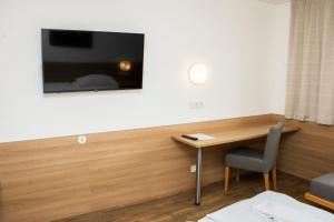 a room with a desk and a television on a wall at OEKOTEL Hohenems in Hohenems