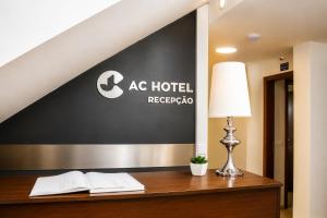 a hotel reception desk with a lamp and two books at AC Hotel in Luanda