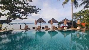 a swimming pool with chairs and umbrellas and the water at Serenity Resort Koh Chang in Ko Chang