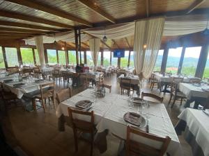 a restaurant with white tables and chairs and windows at Masseria della Fontana Vecchia in San Cipriano Picentino +2 photos
