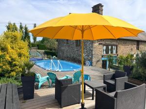 a yellow umbrella sitting on a deck next to a pool at La Cahudiere in Saint-Martin-Landelles