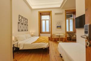 a bedroom with two beds and a flat screen tv at Casa da Praça by PURUS in Coimbra