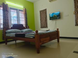 a bedroom with a bed and a tv on the wall at Green Haven Villas in Chennai