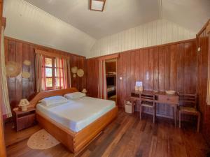 a bedroom with a large bed and wooden walls at Le Renala Morondava in Morondava