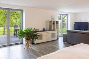 a living room with a bed and a television and sliding glass doors at Spatzenhuus in Rubkow