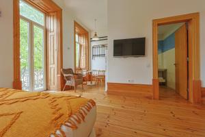 a bedroom with a bed and a television on a wall at Casa da Praça by PURUS in Coimbra