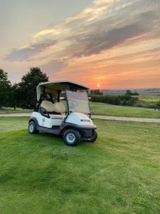a golf cart parked in a field with the sunset at Lontargos OG Wohnung in Göhren-Lebbin +14 photos