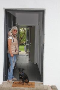 a man standing in a doorway with a dog on a leash at FeWo Atlanta in Reinhardshausen