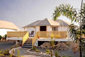 a white house with a porch and stairs to it at Yadus By Alcor in Bīsalpur