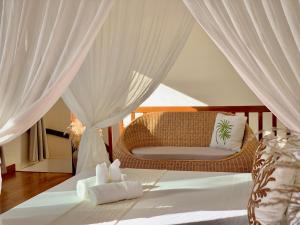 a bedroom with a bed with white curtains and a chair at La Colombine Appart'Hôtel in Sainte Marie +133 photos