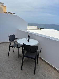 a white table with two chairs and a bottle of wine at Tarelis Beach Apartments & Studios in Kamari
