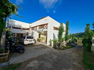 a white house with a car parked in the driveway at Villa August Lombok in Selong Belanak