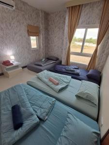 two twin beds in a room with a window at Minie House Hatyai in Hat Yai