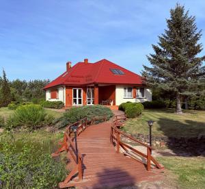 a house with a red roof and a wooden walkway at Willa u Bociana in Siemianówka