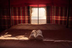 a pair of shoes on a bed in front of a window at Ocean Camp in Al Qārin