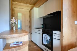 a kitchen with white cabinets and a black stove at Mein Refugium Relax Tiny Haus in Unteriberg