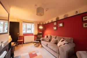 a living room with a couch and a red wall at Green Beck Cottage, within walking distance of the lake, shops, pubs & restaurants of Coniston in Coniston
