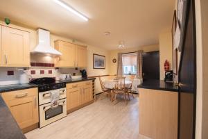 a kitchen with wooden cabinets and a black counter top at Green Beck Cottage, within walking distance of the lake, shops, pubs & restaurants of Coniston in Coniston +18 photos