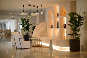 a lobby with white chairs and a couch and a table at Alua Leo in Can Pastilla