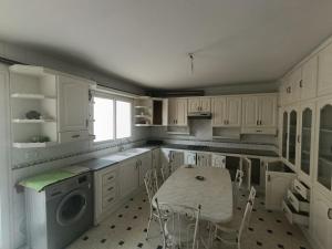 a kitchen with white cabinets and a table and chairs at Cozy house in Nabeul