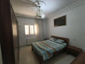 a bedroom with a bed and a chandelier at Cozy house in Nabeul