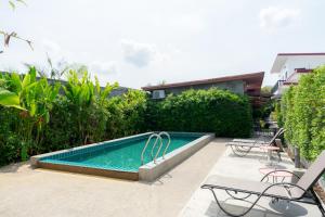 a swimming pool with two chairs and a table at Malinee Resort in Bang Tao Beach