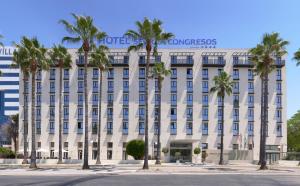 a white building with palm trees in front of it at M.A. Hotel Sevilla Congresos in Seville
