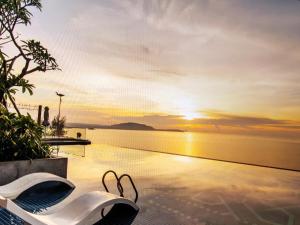 a pair of white shoes sitting on a pool with a sunset at Pristine Coast Residences in Phan Thiet
