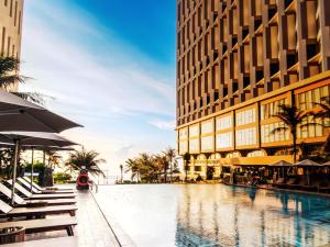 a hotel swimming pool in front of a building at Pristine Coast Residences in Phan Thiet