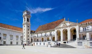 a large building with a clock tower in front of it at Casa da Praça by PURUS in Coimbra
