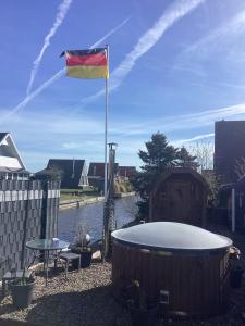 a flag flying over a bath tub next to a pond at Ferienhaus Ankerplatz in Bedekaspel