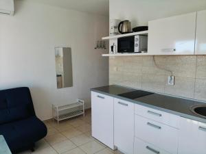 a kitchen with white cabinets and a blue chair at Apartments Malou in Baška Voda